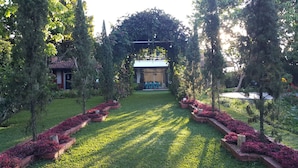 A garden pathway leading to a building with a covered seating area. - Vila Bunga Merah Gelatik (Lembang)