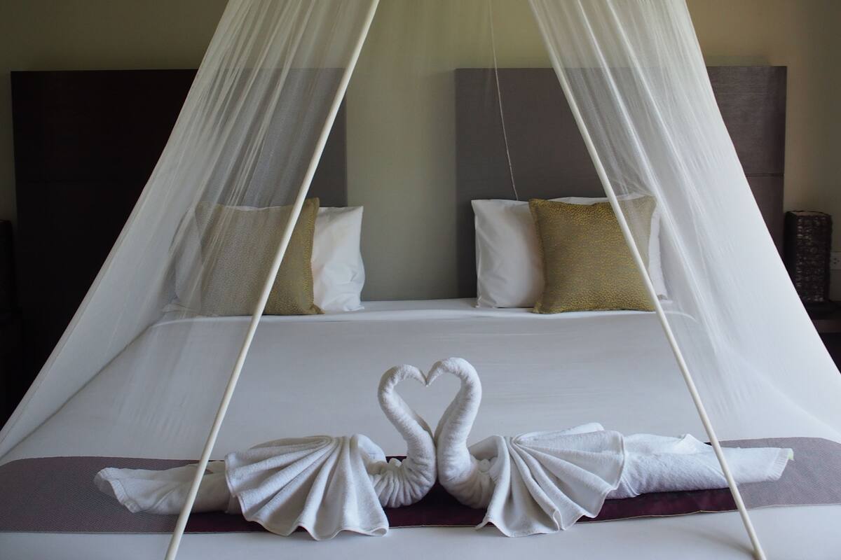 A bed with a canopy and swan-shaped towels.