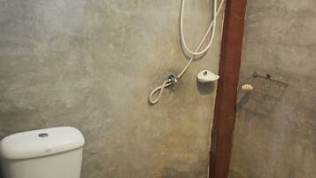 A bathroom with a toilet, a shower unit, and a tiled floor.