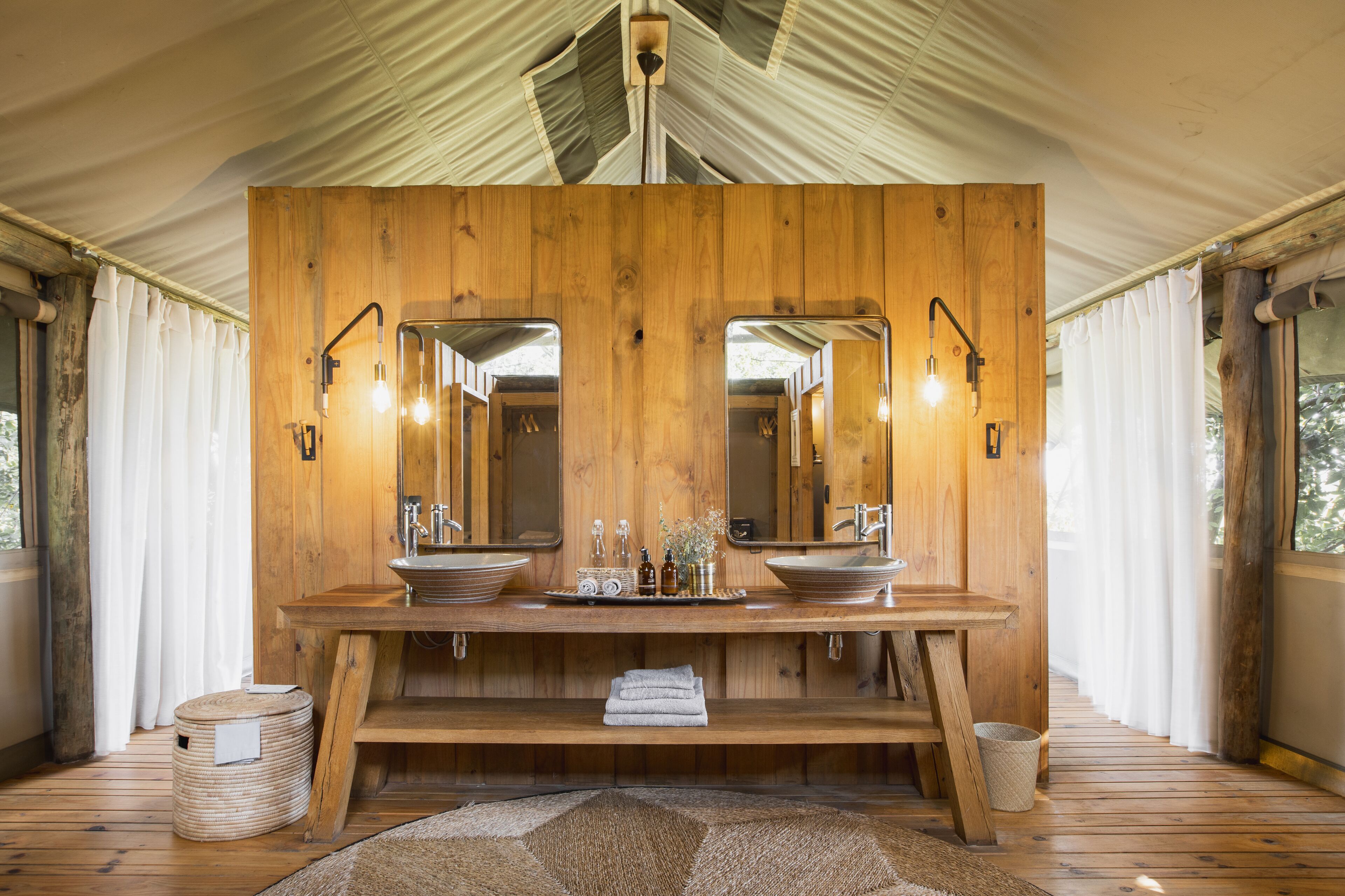 A wooden vanity with two sinks, mirrors, and a light fixture.