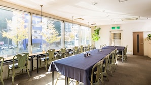 A conference room with a long table, chairs, and large windows with a view of the street. - Hotel Sungarden Matsuyama (Matsuyama)