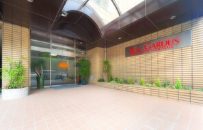 The exterior of Sun Garden Hotel Matsuyama with a modern design, including a glass entrance and a tiled walkway. - Hotel Sungarden Matsuyama (Matsuyama)