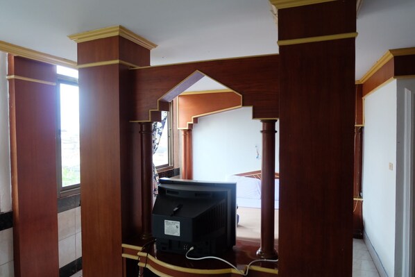 A hallway with wooden columns and a television set in the center. - Satit Padang Hotel (Sadao)