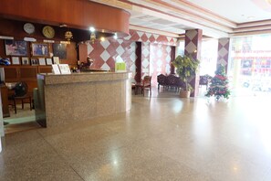 A hotel reception area with a marble counter, wooden furniture, and a Christmas tree. - Satit Padang Hotel (Sadao)