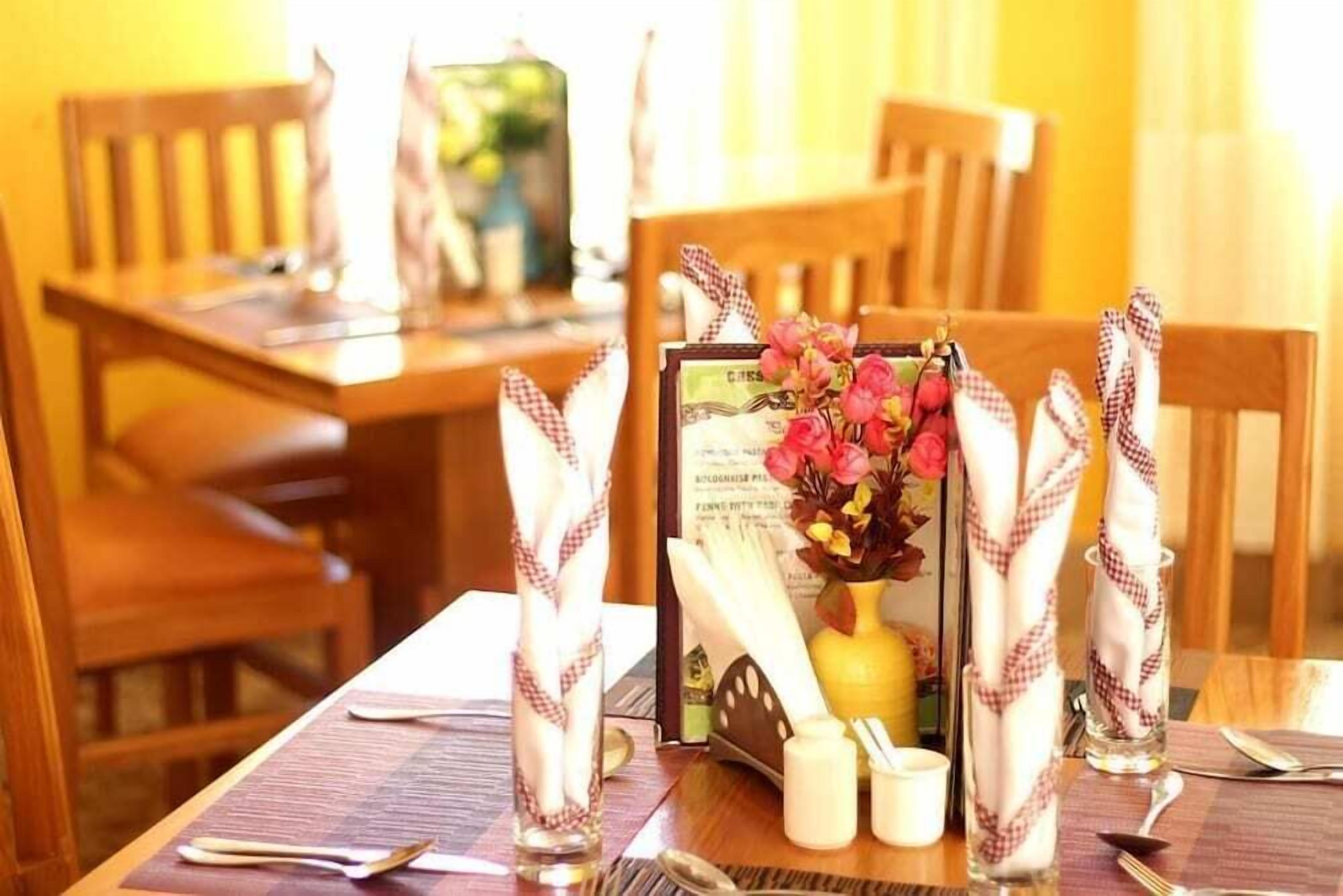 Una mesa de comedor con servilletas de cuadros, un florero con flores y un menú.