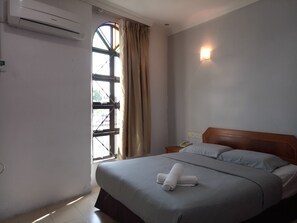 A hotel room with a bed, a nightstand, a telephone, and a window with curtains. - Sherwinton Hotel (Mentakab)