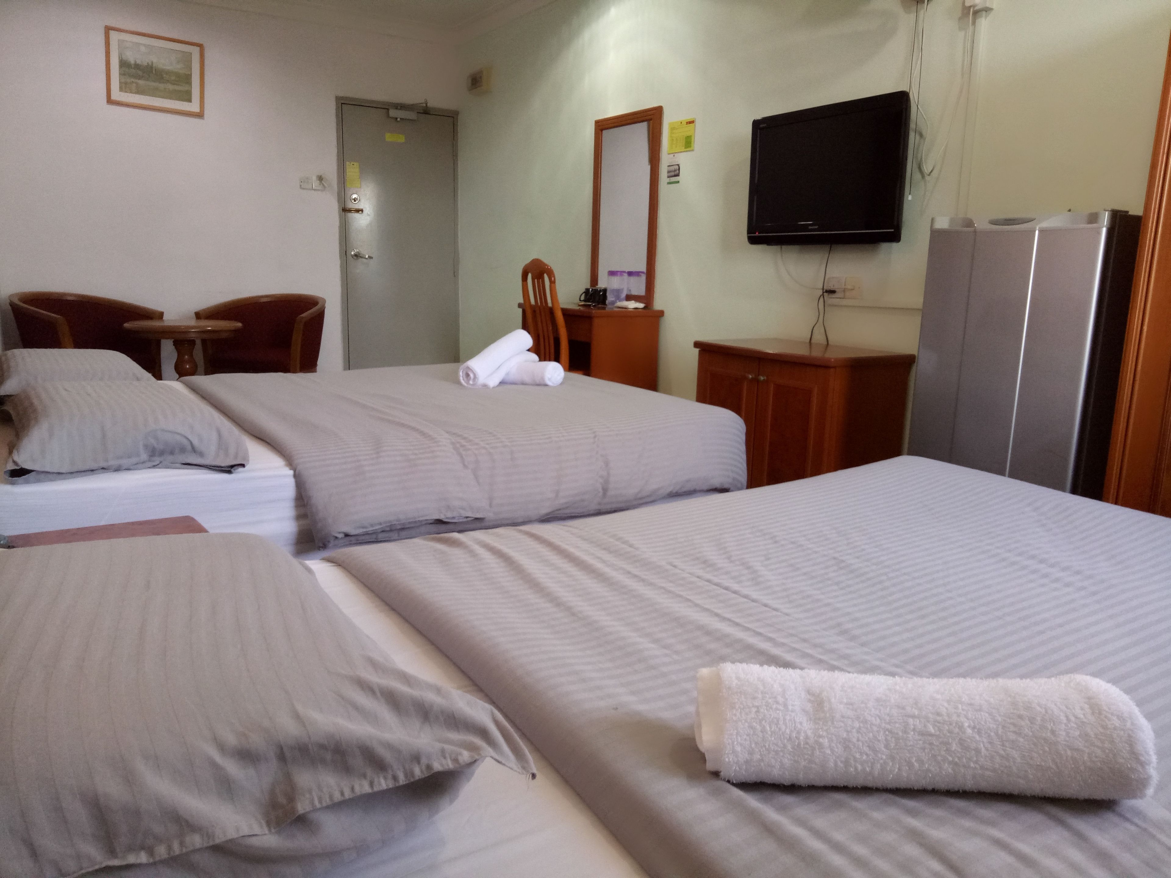 A hotel room with two beds, a television, a desk, and a chair.