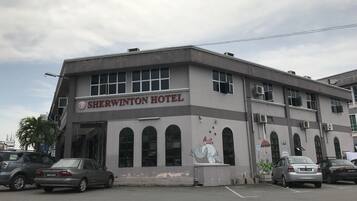 A Sherwinton Hotel with a simple facade, multiple windows, and a parking lot with several cars.