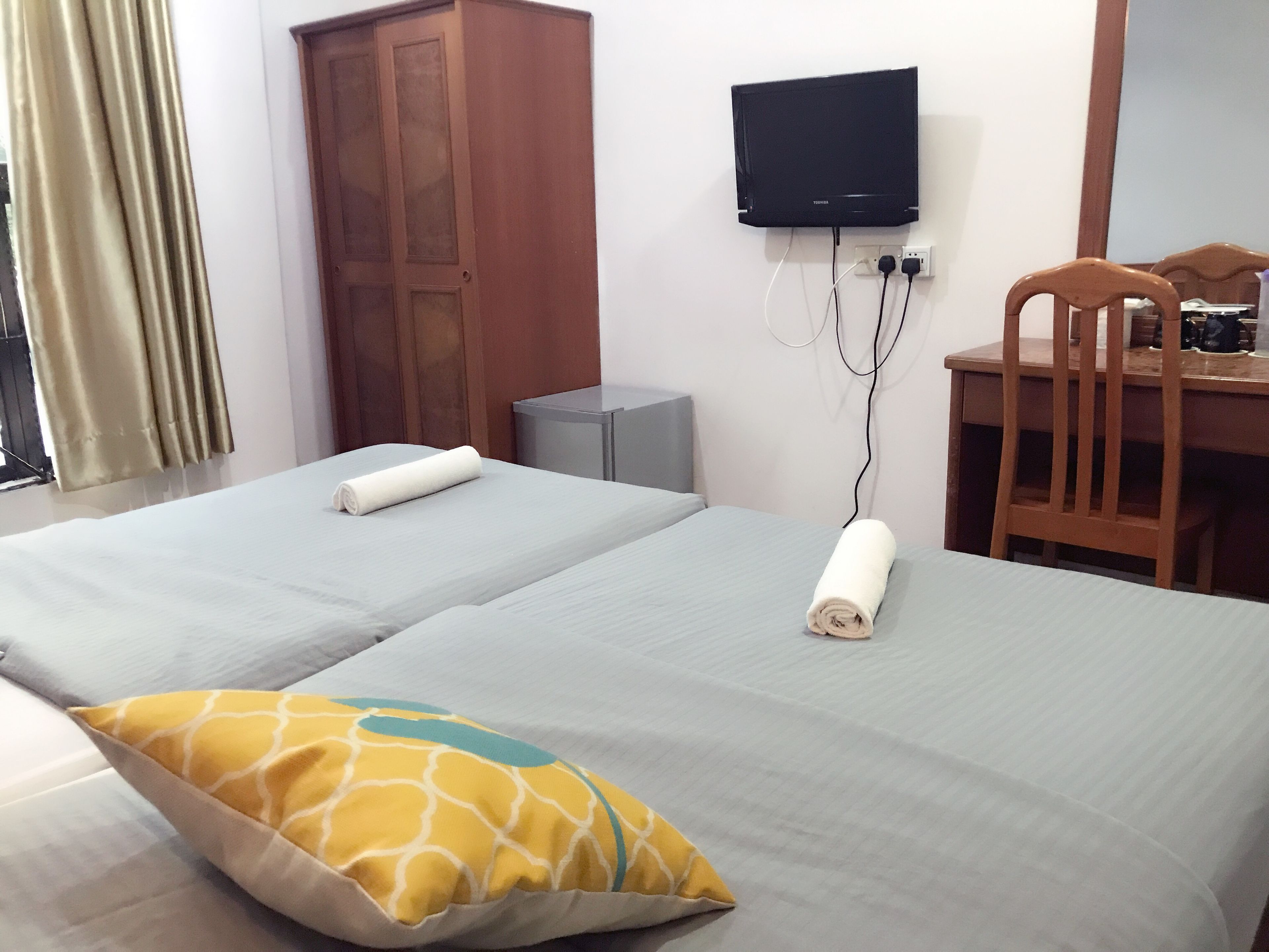 Habitació d'hotel amb dos llits, una televisió penjada a la paret, un escriptori i una cadira.