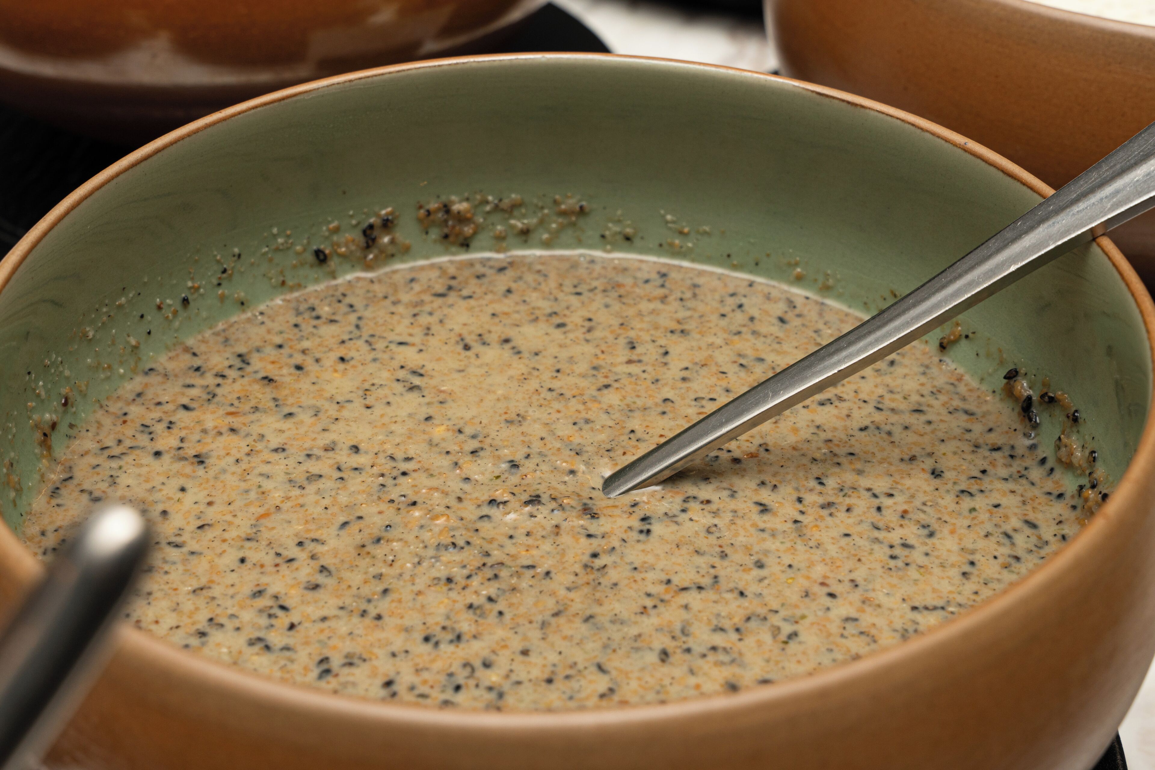 A bowl with a spoon in it, possibly containing a soup or stew.