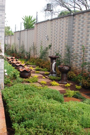 A garden with potted plants and a brick wall. - The Panari Residence (Nairobi)
