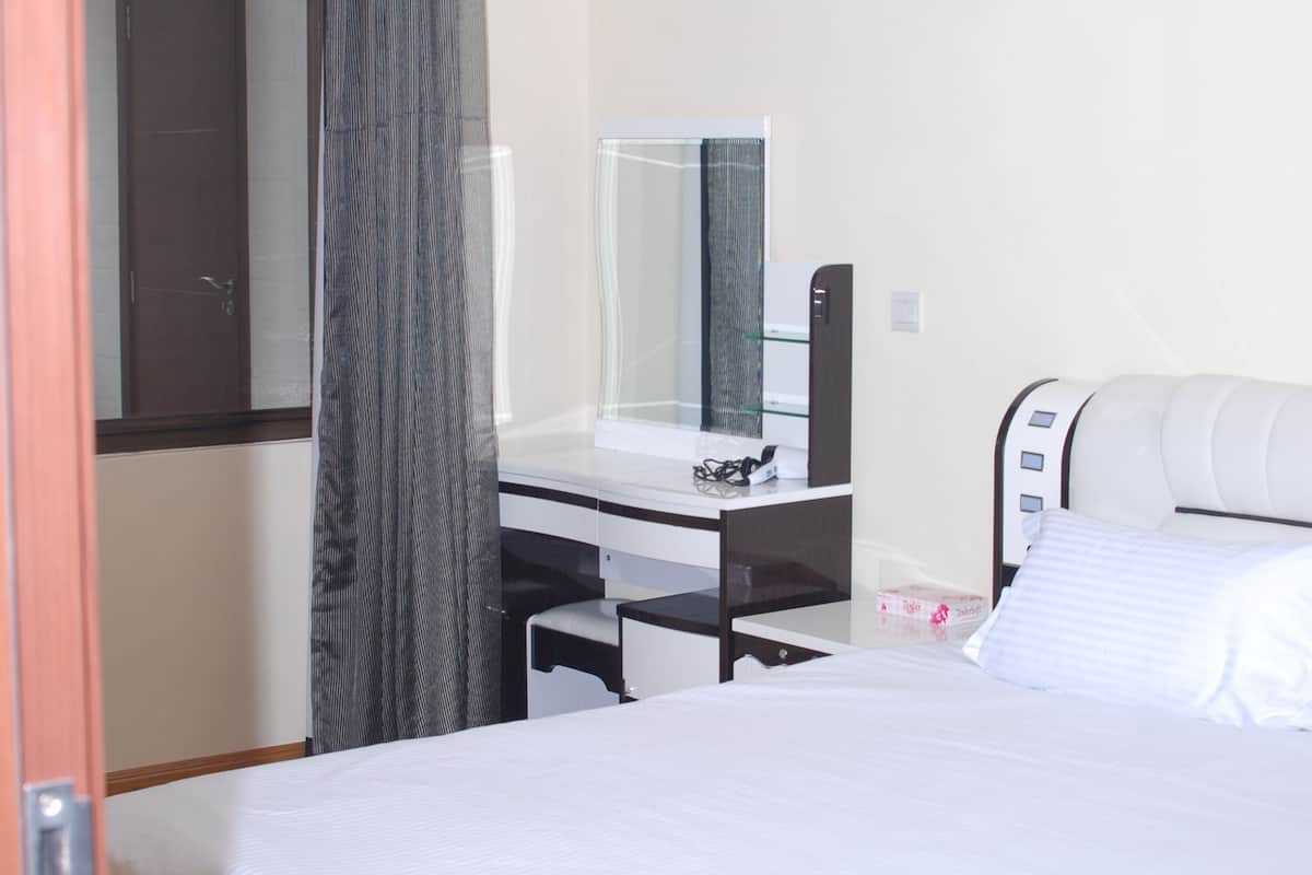 Habitación de hotel con cama, escritorio con espejo y ventana con cortinas.