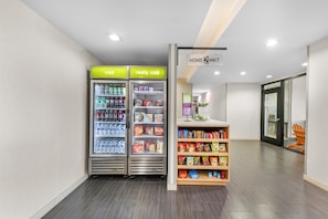 Un interior moderno y limpio con dos dispensadores de bebidas etiquetados 'frío' y 'muy frío', y una repisa con varios productos para el aperitivo.