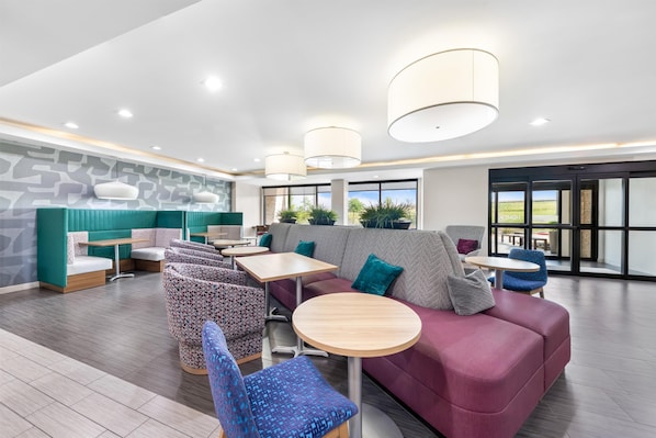 Un espacio lounge moderno con asientos, mesas y ventanas amplias.