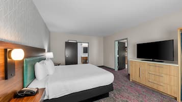A hotel room with a bed, bedside table, lamp, telephone, television, wardrobe, and a mirror.
