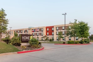 Un moderno edificio de hotel con un letrero que indica 'HOME SUITES BY HILTON' y una bandera.