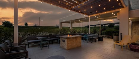 Un patio al aire libre con un brasero, asientos e iluminación colgante.