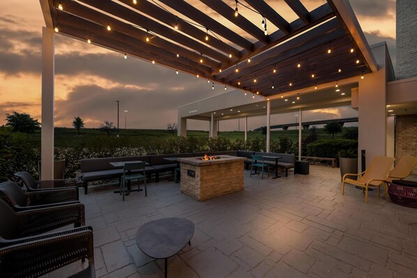 Eine Terrasse im Freien mit Feuerstelle, Sitzgelegenheiten und Lichterkette.