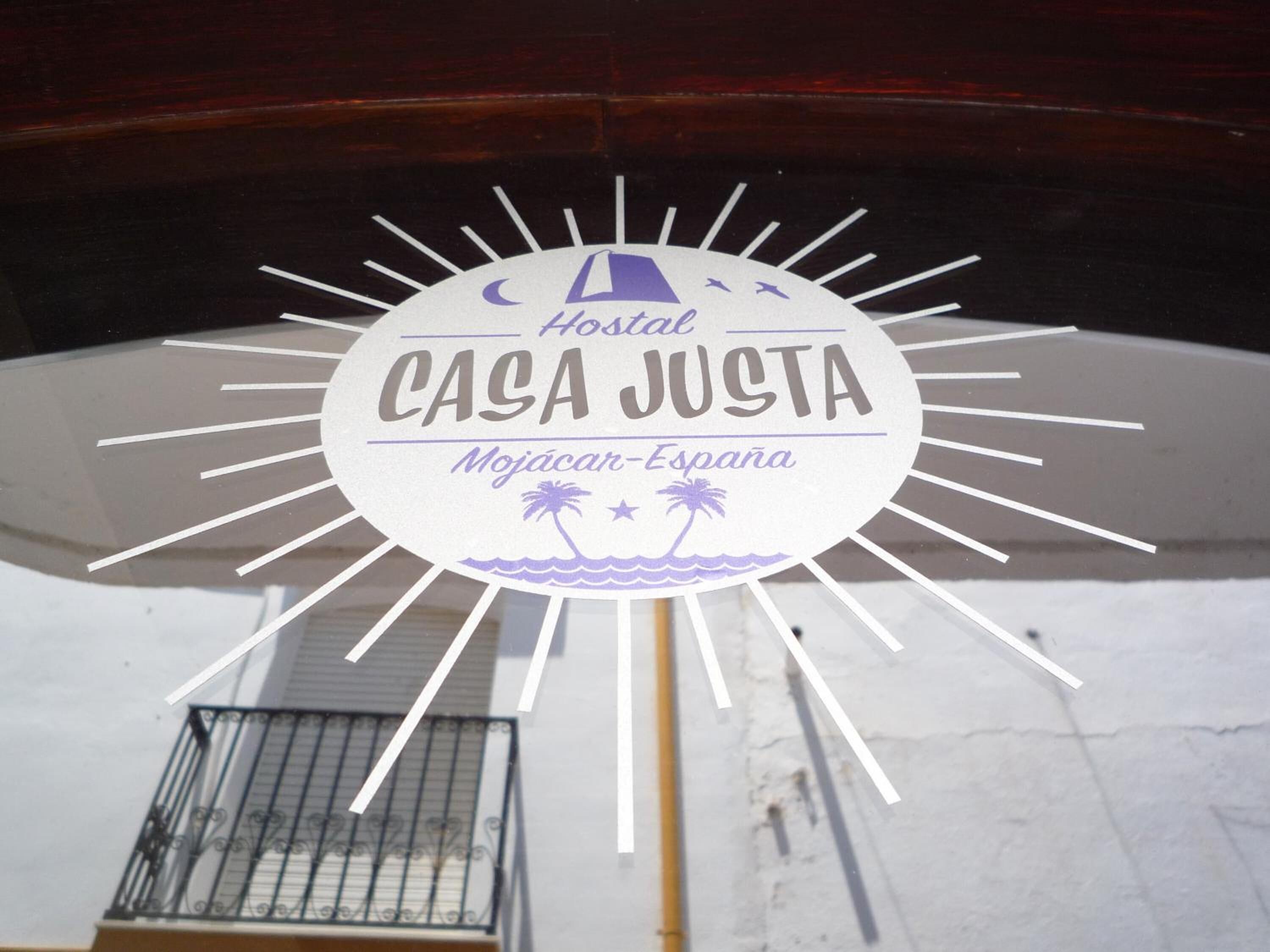 Una señal circular con el texto 'Hostal CASA JUSTA' y 'Mojácar-España', que indica el nombre de un hotel y su ubicación.