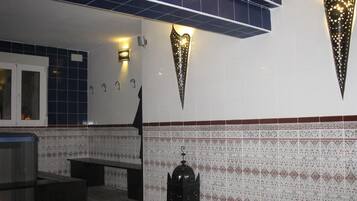Uma casa de banho com azulejos estampados, um banco e um ornato na parede.