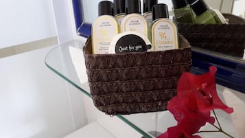 A bathroom shelf with a basket containing several bottles of Taylor of London bath and shower gel, a card with the text "Just for you," and a red flower.