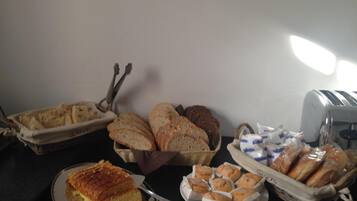 Una mesa de buffet con panes, pasteles y un pastel.