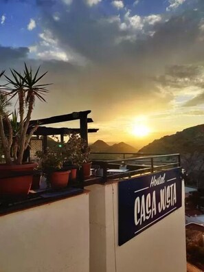 A sign for 'Hostal CASA JUSTA' with a view of the sunset and mountains in the background. - Hostal Casa Justa (Mojacar)