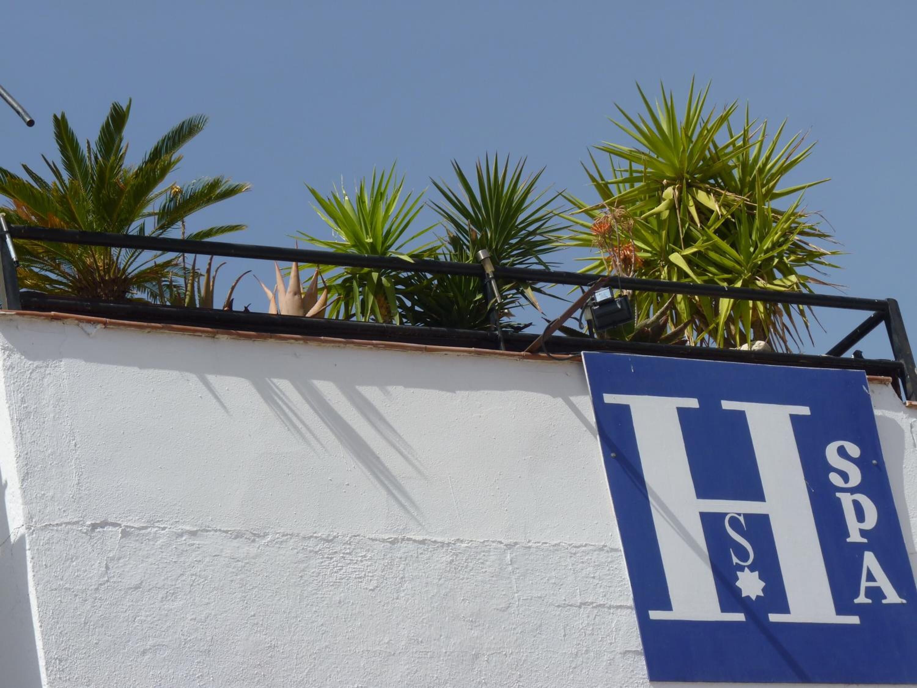 A sign with the letters "H" and "SPA" on a white wall, indicating a hotel or spa.