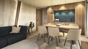 A modern living room with a dark sofa, a round coffee table, and a dining area with a wooden table and four chairs. - Aparthotel Kronplatz Luxury House (Valdaora)