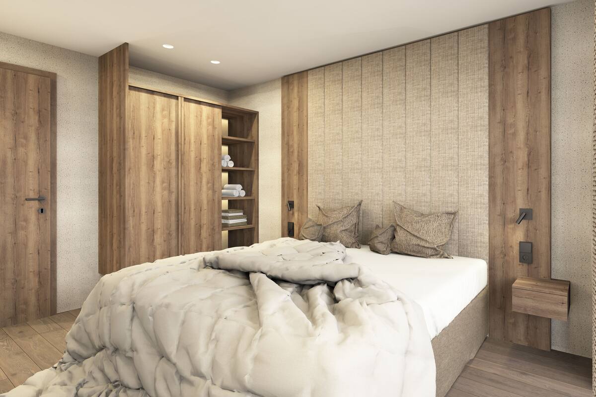 A bedroom with a bed, wooden wardrobe, and built-in shelving.