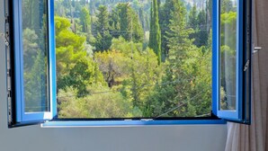 A room with a table and chairs, a window with an open view of a forested landscape.