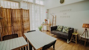 A room with a dining table, a sofa, a wall-mounted clock, and a sign reading "ESTACAO DO PARQUE". - Estação do Parque (Santa Maria da Feira)