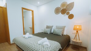 A bedroom with a bed, a bedside table, a lamp, and a mirror. - Estação do Parque (Santa Maria da Feira)