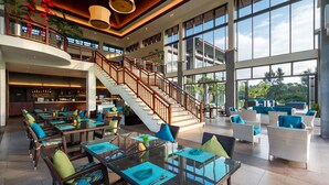A spacious indoor area with multiple dining tables, a staircase, and large windows offering views of the outdoors. - Laguna Parkside Lăng Cô (Hue)