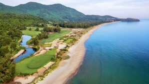 A coastal golf course with a beach, a lake, and mountains in the background. - Laguna Parkside Lăng Cô (Hue)