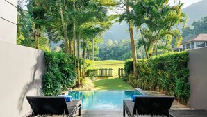 A pool area with lounge chairs, surrounded by lush greenery and a view of a golf course. - Laguna Parkside Lăng Cô (Hue)