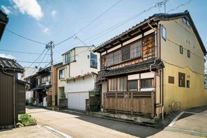 A traditional Japanese residential street with wooden houses, a clear sky, and visible power lines. - Hisago (Kanazawa)