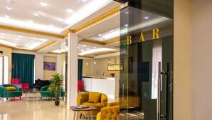A hotel lobby with a reception desk, a bar, and seating areas with green and yellow chairs. - Hotel Grand Palace Tbilisi (Tbilisi)