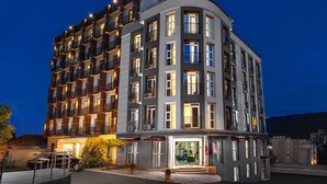 A multi-story hotel with balconies, a ground-level entrance, and a parking area. - Hotel Grand Palace Tbilisi (Tbilisi)