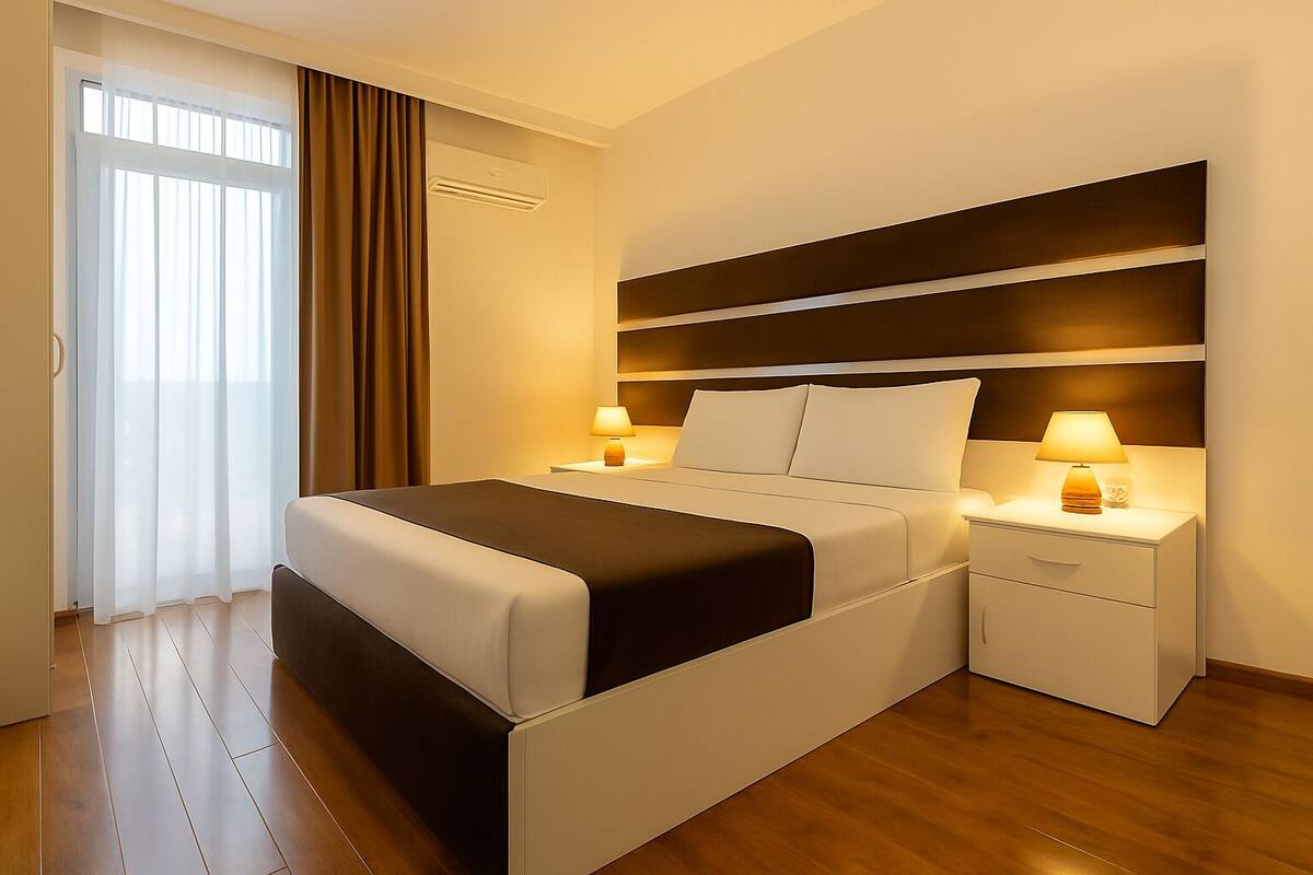 Una habitación de hotel moderna con cama, mesitas de noche y un ventanal con cortinas.