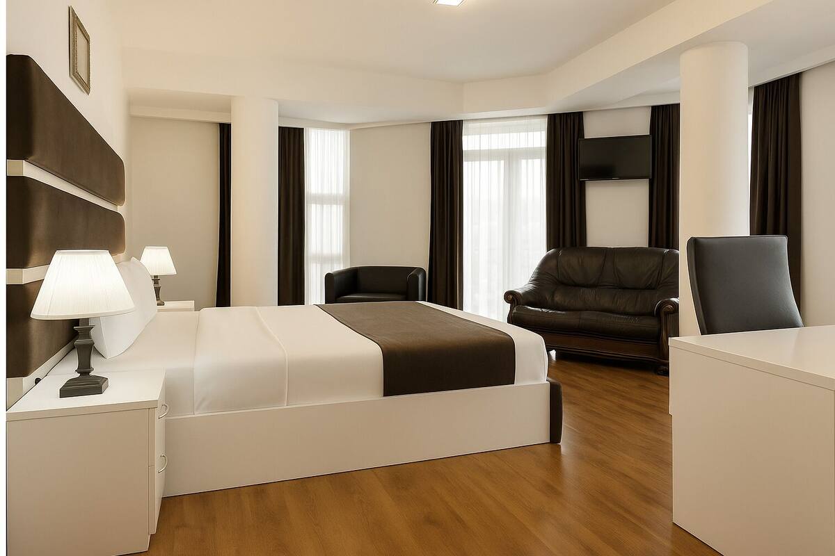Una habitación de hotel con una cama, dos sillas, un escritorio y un televisor.