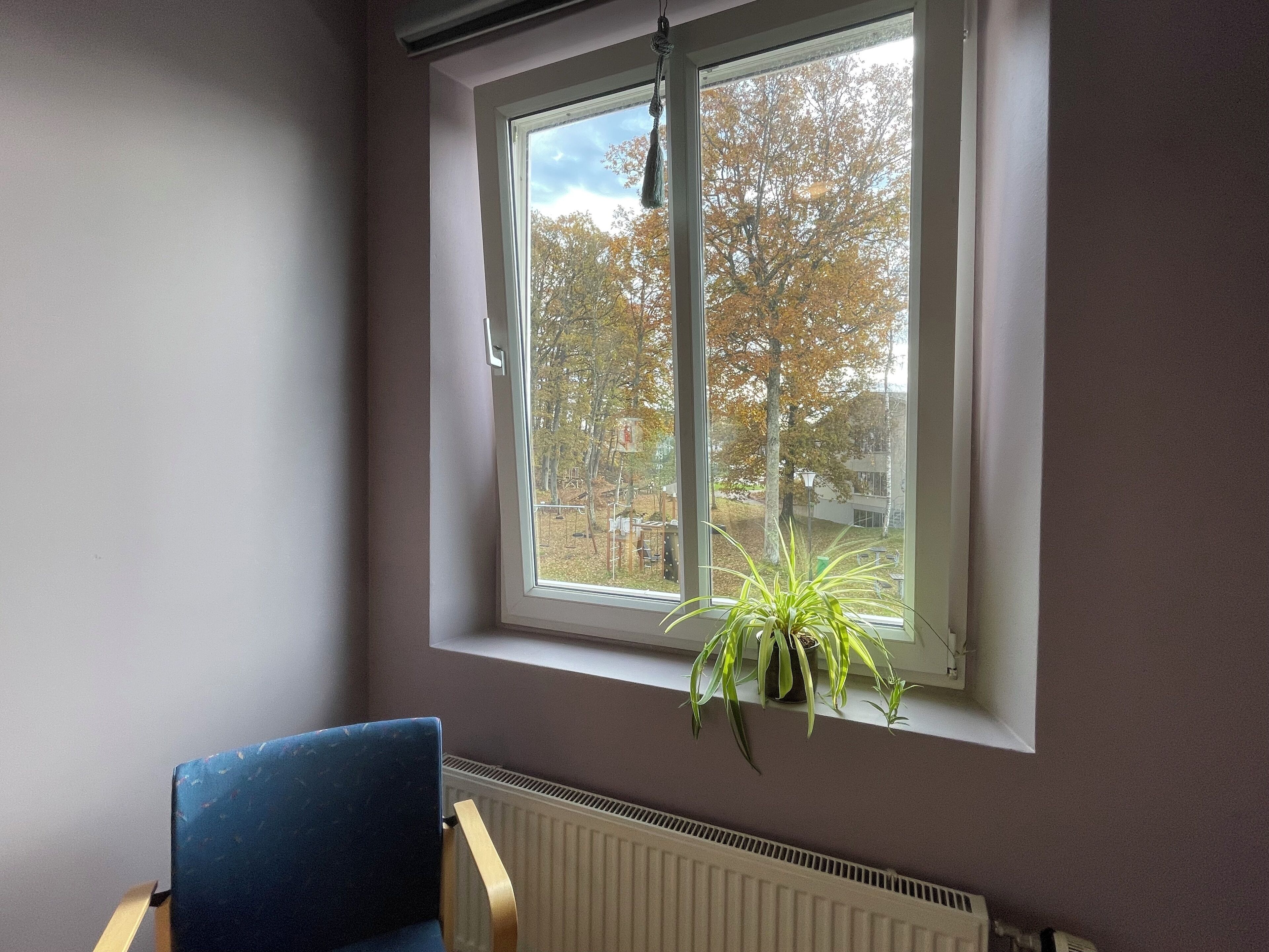 Une pièce avec une fenêtre, une chaise et un radiateur.