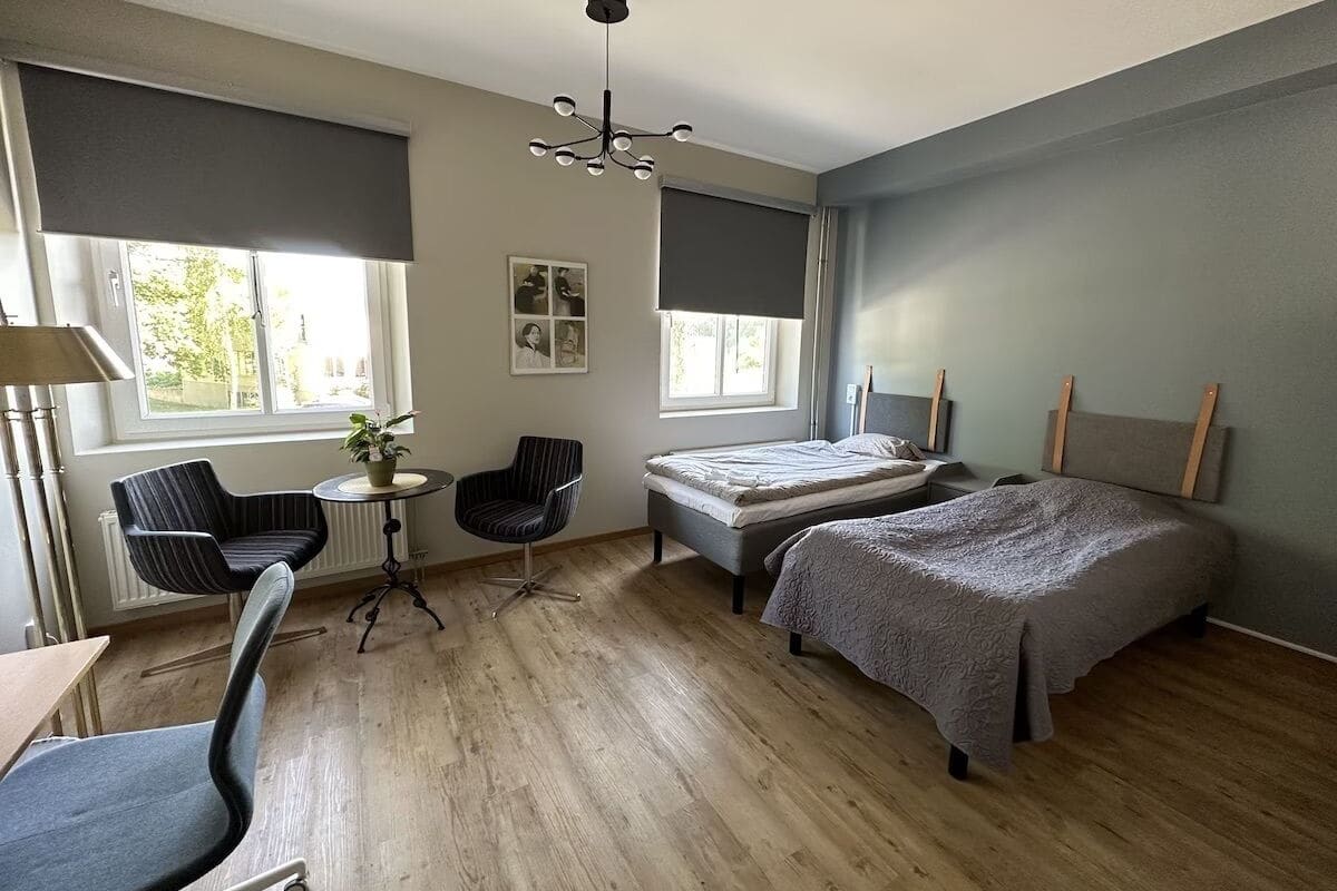 Un dormitorio moderno con una cama, dos sillas, una mesita y una lámpara en el techo.