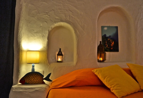 Una habitación con una cama, dos lámparas de pared y una lámpara con forma de pez.