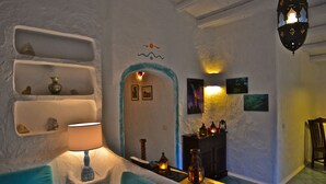 A cozy room with a fireplace, shelves with decorative items, a lamp, and a blue chair. - Poecylia Resort (Carloforte)