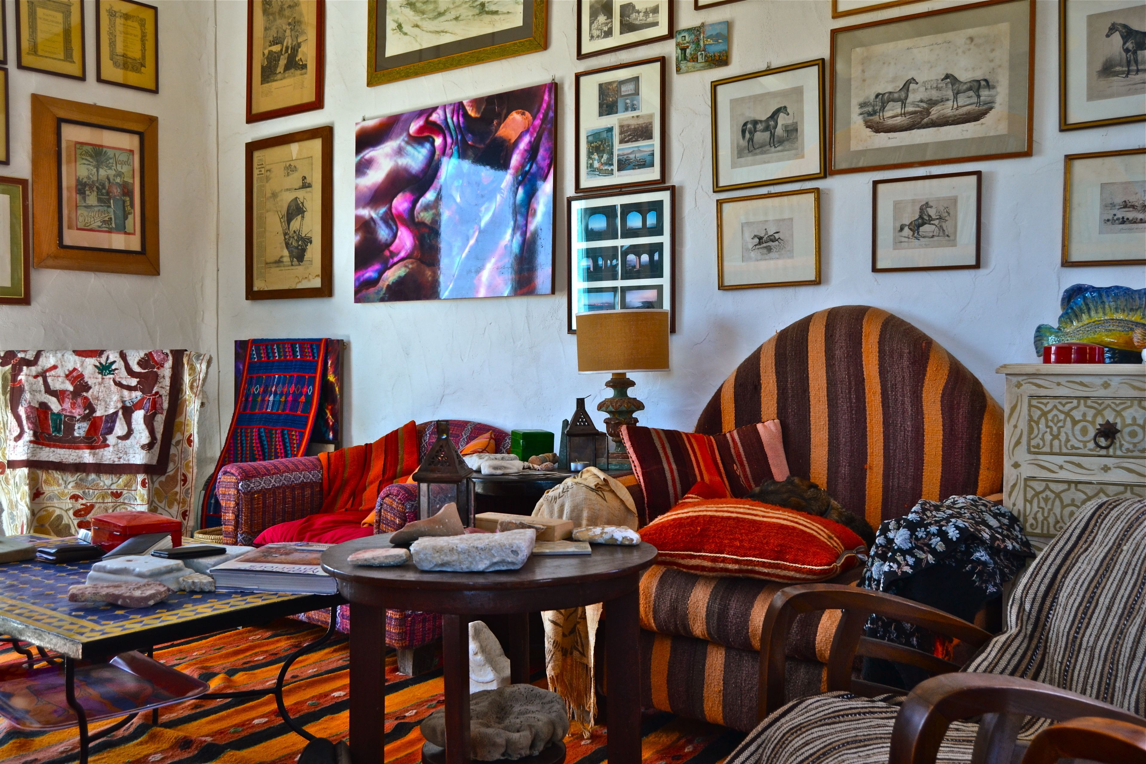 A cozy living room with a striped sofa, a patterned rug, and various framed artworks on the walls.