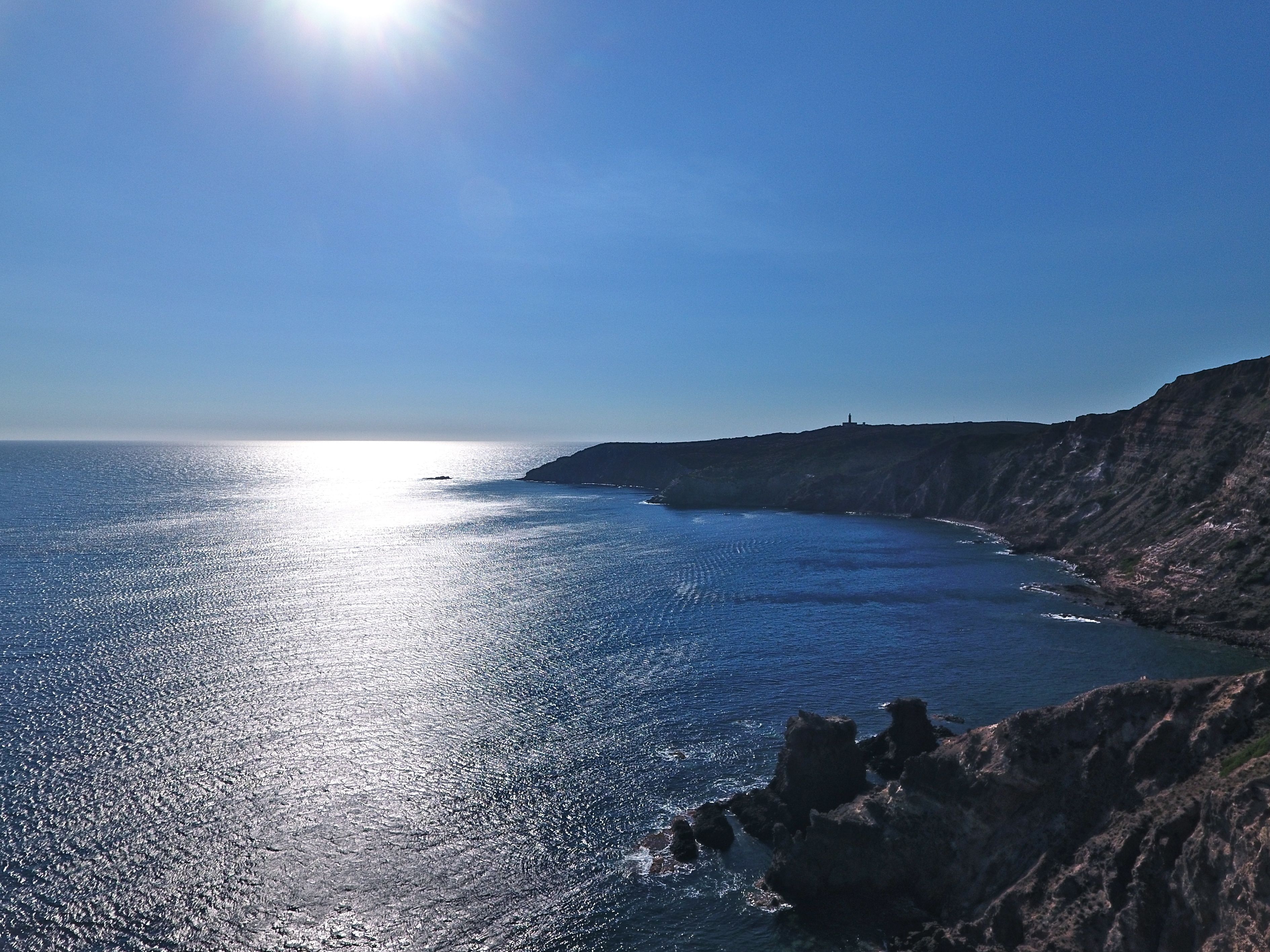 Un paisaje costero con cielo despejado, mar tranquilo y acantilados rocosos.