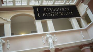 Schild für Restaurant und Rezeption in einem Gebäude mit Balkon und weißen Säulen.
