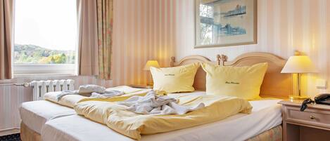 A hotel room with a bed, a nightstand, a lamp, and a painting on the wall.