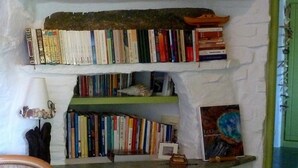 A cozy reading nook with a chair, a bookshelf filled with books, and a small table with a lamp. - La Maison Vert Amande (Kea)
